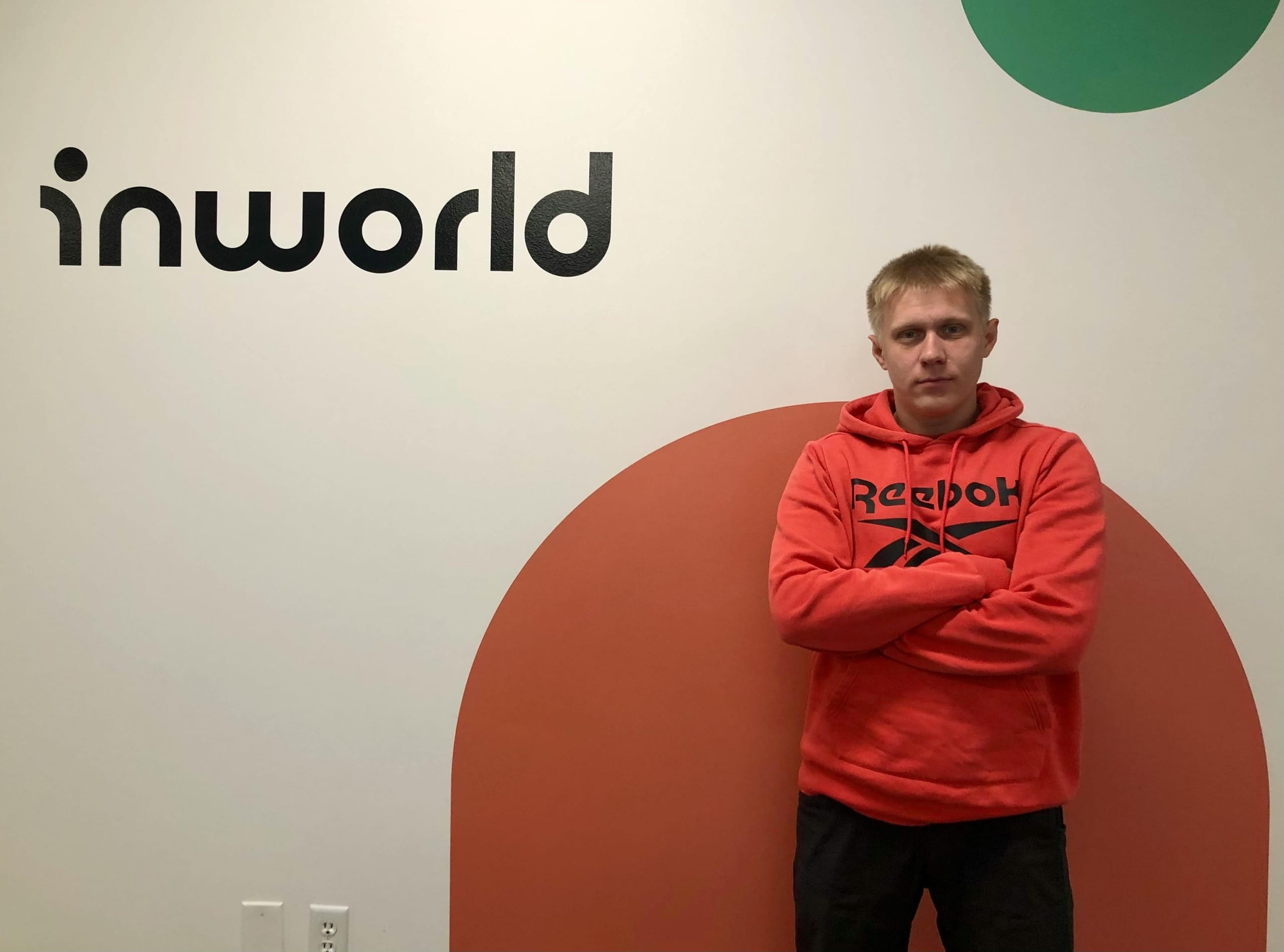 A man is standing in front of the wall with Inworld logo on it
