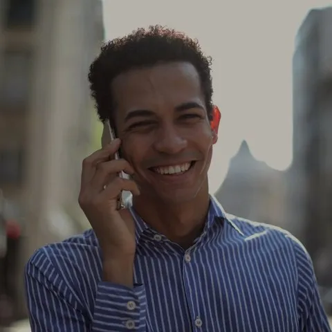 A man on a city crossing, talking into his phone