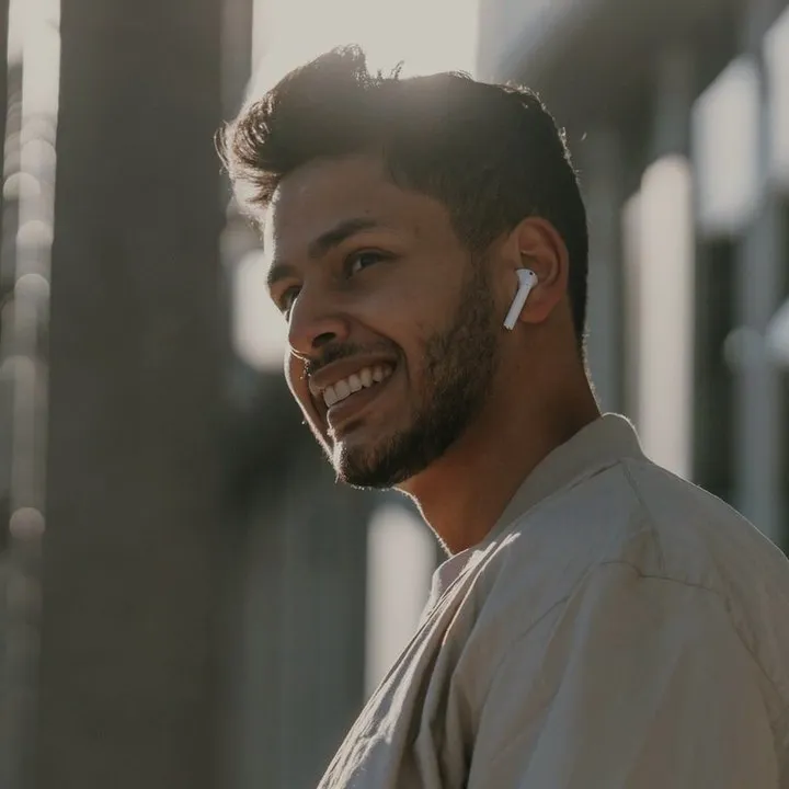 A man listening on earbuds, smiling