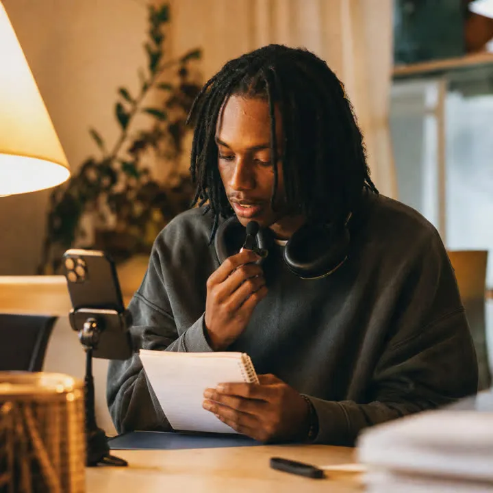 A man recording his voice on a phone at his desk